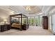 Spacious main bedroom features a tray ceiling, a four-poster bed, and large windows for natural light at 8295 St Marlo Fairway Dr, Duluth, GA 30097