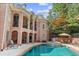 View of the pool with stone features, next to the brick exterior with balconies and outdoor seating at 8295 St Marlo Fairway Dr, Duluth, GA 30097
