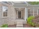 A close-up view of the front porch with brick steps, white pillars, and a dark front door at 554 Grand Ashbury Ln, Sugar Hill, GA 30518