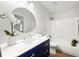 A bright bathroom with a blue vanity, round mirror, and a shower-over-tub combination at 2435 Northlake Ct, Atlanta, GA 30345