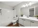Well-lit bathroom featuring a tiled tub, toilet, and a modern vanity with dark hardware at 2435 Northlake Ct, Atlanta, GA 30345