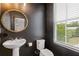 Stylish powder room with dark walls, round gold-accented mirror, and white pedestal sink at 2808 Maddison Towns Ave, Norcross, GA 30071