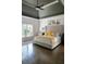 A spacious bedroom features a decorative tray ceiling, a tufted headboard, and hardwood floors at 4046 Creekview Ridge Dr, Buford, GA 30518