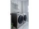 Laundry room with modern, stainless front-loading washer and dryer and white cabinets above at 4046 Creekview Ridge Dr, Buford, GA 30518