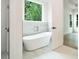 Bright bathroom features a soaking tub under a window with a view of trees at 4824 Se Highway 20, Conyers, GA 30013