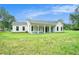 Rear view of a bright white, modern farmhouse featuring a covered back porch and spacious yard at 4824 Se Highway 20, Conyers, GA 30013