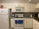 Well-lit kitchen with white appliances, cabinetry, and a gray countertop at 5570 Chemin De Vie, Atlanta, GA 30342