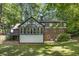 Expansive backyard view of the home featuring a sunroom, deck, and lush green lawn surrounded by mature trees at 965 Heards Ferry Rd, Sandy Springs, GA 30328