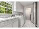 Well-lit laundry room with modern washer and dryer, sink, storage cabinets, and a window view of lush greenery at 965 Heards Ferry Rd, Sandy Springs, GA 30328