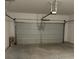 An open garage area with gray door, storage, and concrete flooring at 1001 Limburg Dr, Hampton, GA 30228