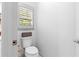 Clean powder room features toilet, white walls, white trim, and a window for natural light at 208 Wade Creek Rd, Alpharetta, GA 30009