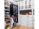 Organized walk-in closet with custom shelving, drawers, cabinets, hanging rods, and wood floors at 208 Wade Creek Rd, Alpharetta, GA 30009