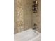 Modern bathroom featuring a white bathtub with tiled walls and decorative stone accents at 710 Oxford Crest Ct, Lawrenceville, GA 30043