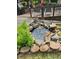 A rock lined backyard water feature with mature landscaping in a well-maintained yard at 710 Oxford Crest Ct, Lawrenceville, GA 30043