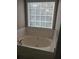Relaxing bathroom showcasing a large soaking tub with tile surround and a window at 2775 Emerald Springs Dr, Lawrenceville, GA 30045