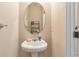 Clean half-bathroom featuring a pedestal sink, an oval mirror, and neutral-colored walls at 3829 Thayer Trce, Duluth, GA 30096