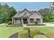 Inviting brick home featuring a landscaped front yard with mature trees and a cozy front porch with chairs at 7070 Concord Mountain Trl, Cumming, GA 30028