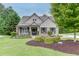 Charming brick home with well-manicured lawn, mature trees, and inviting front porch with outdoor seating at 7070 Concord Mountain Trl, Cumming, GA 30028