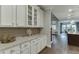 Kitchen showcasing white cabinets, stone countertops, and view of an adjacent living space at 7070 Concord Mountain Trl, Cumming, GA 30028
