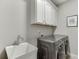 Bright laundry room featuring white cabinets, utility sink, and modern washer and dryer at 7070 Concord Mountain Trl, Cumming, GA 30028