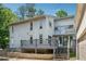 Two-story home with a grey back deck and stairs, surrounded by lush trees at 4117 Signal Sw Rdg, Lilburn, GA 30047