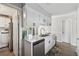 Well-lit kitchen boasts white cabinets and stainless steel appliances with an adjacent laundry room at 4117 Signal Sw Rdg, Lilburn, GA 30047