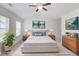 This staged main bedroom features neutral decor, natural light, and an overhead fan at 7682 Baron Rd, Fairburn, GA 30213