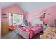 Pink bedroom with decorative wall art, shelving, and a bed with colorful bedding at 543 Walnut Way, Palmetto, GA 30268