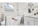 Bright bathroom with marble walls, soaking tub, frosted window, white vanity, and modern fixtures at 1450 Elizabeth Ln, Atlanta, GA 30344