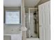 Clean bathroom features a walk-in shower, white tiled walls, and a window allowing natural light at 1627 Amhearst Walk Rd, Lawrenceville, GA 30043