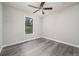Comfortable bedroom with gray wood floors, a ceiling fan, and a view of the outside scenery at 3066 Malvern Dr, Snellville, GA 30039