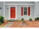 A closer view of the home's entrance, showcasing a red front door with classic white trim and manicured landscaping at 3999 Bayside Cir, Doraville, GA 30340
