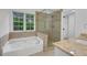 Bright bathroom with jacuzzi tub, glass shower and granite vanity top at 4009 Riverstone Dr, Suwanee, GA 30024
