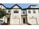Stylish townhomes featuring white brick exteriors, black trim, and modern garage doors at 32 S Auburn Landing Pl, Auburn, GA 30011