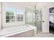 Bright bathroom with a soaking tub, glass shower, and large window at 650 Garden Wilde Place, Roswell, GA 30075