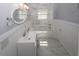 Bright bathroom featuring a marble tiled shower, a round mirror, and white wainscoting at 1110 Mcdaniel Sw St, Atlanta, GA 30310