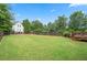 Large, lush backyard with a fenced perimeter, mature trees, and a charming stable structure at 4530 Westgate Dr, Cumming, GA 30040