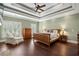 Bedroom with wood flooring, tray ceiling, plantation shutters, and sitting area at 4530 Westgate Dr, Cumming, GA 30040