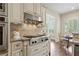 Kitchen with stainless steel stove top, range hood, tile backsplash, and granite countertops at 4530 Westgate Dr, Cumming, GA 30040