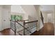 A staircase with wrought iron railing and hardwood floors is illuminated by a window and chandelier at 4530 Westgate Dr, Cumming, GA 30040