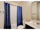 A clean bathroom featuring a shower with blue curtains, a toilet, and a sink with a marble countertop at 3746 Okefenokee Rdg, Loganville, GA 30052