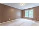 Bedroom featuring tan carpet, tan walls, and a large window with green views at 3801 Stonebriar Ln, Duluth, GA 30097