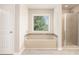 Bright bathroom with a glass-door shower, bathtub, window, and a light wood grain floor at 726 Independence Ln, Acworth, GA 30102
