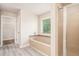 Modern bathroom with a glass-door shower, bathtub, window, and a light wood grain floor at 726 Independence Ln, Acworth, GA 30102