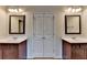 Bright bathroom with dual sinks, dark wood vanities, decorative mirrors, and a double door closet at 1205 Apple Blossom Dr, Cumming, GA 30041