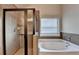 Bathroom featuring a glass-enclosed shower, soaking tub, and tile surround at 1205 Apple Blossom Dr, Cumming, GA 30041