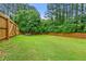 Expansive backyard with green grass, mature trees and wooden privacy fence at 6655 Manchester Pl, Cumming, GA 30040