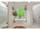 Bright bathroom featuring a freestanding tub beneath a window, complemented by a glass-enclosed shower at 6655 Manchester Pl, Cumming, GA 30040