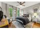 Elegant bedroom with plush bedding, decorative pillows, complemented by bright windows and a ceiling fan at 6655 Manchester Pl, Cumming, GA 30040