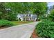 View of home with mature landscaping and a driveway leading to an inviting front porch and double-door entry at 6655 Manchester Pl, Cumming, GA 30040